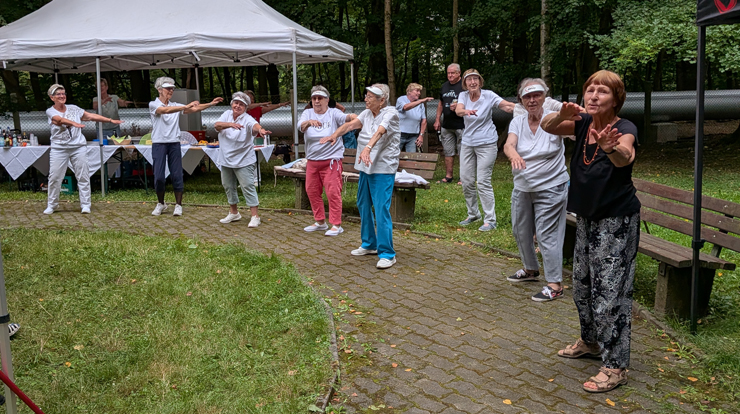 Viele Menschen tanzen gemeinsam auf einer Wiese.