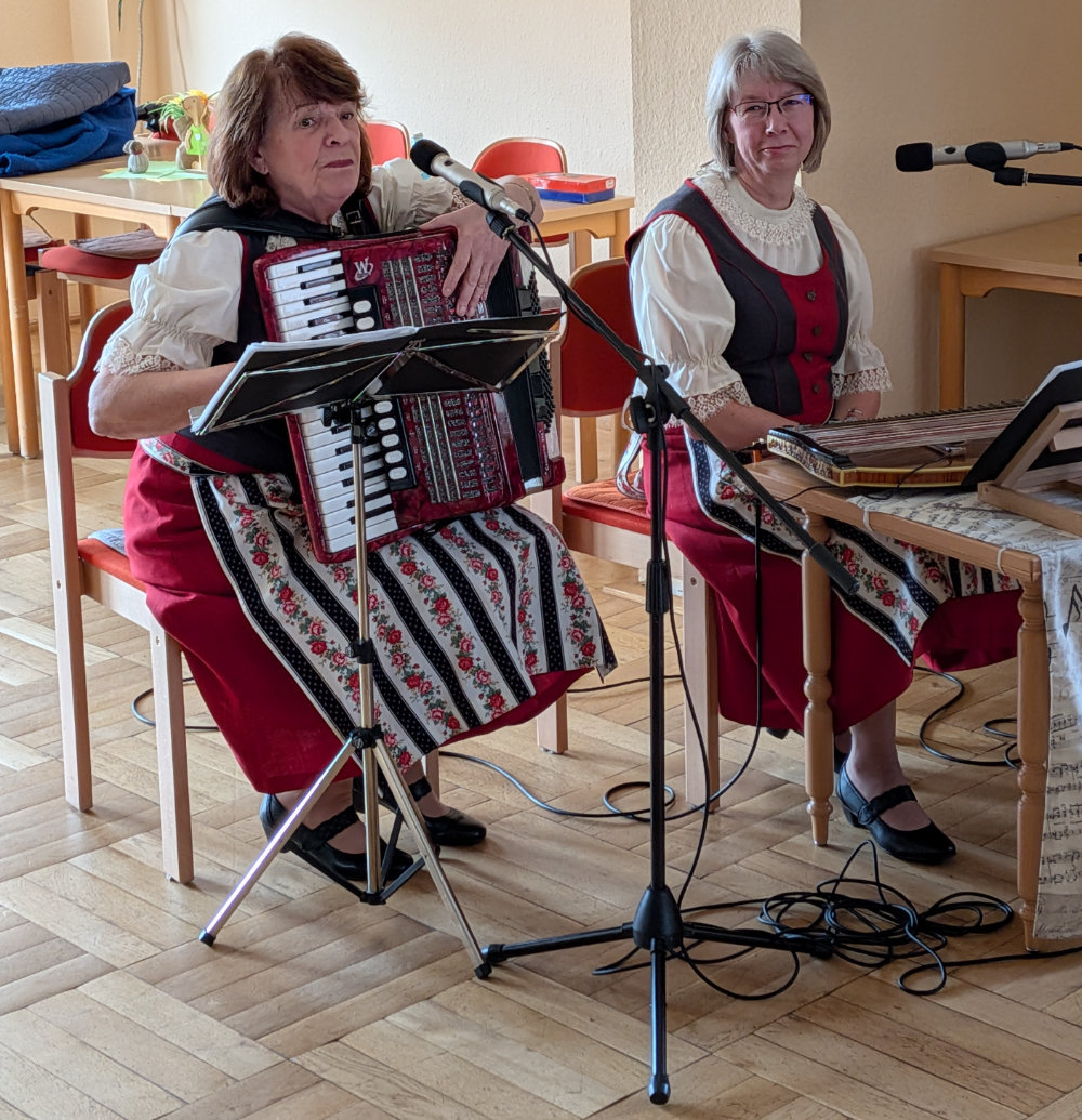 Zwei Frauen spielen Akkordeon und Zitter.